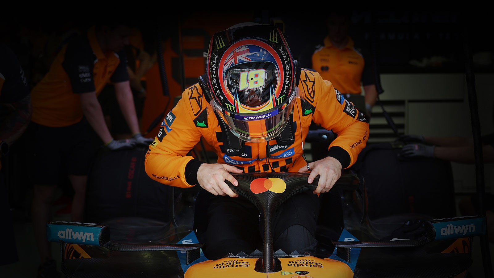 A McLaren F1 Team member adjusts the steering on a racecar.