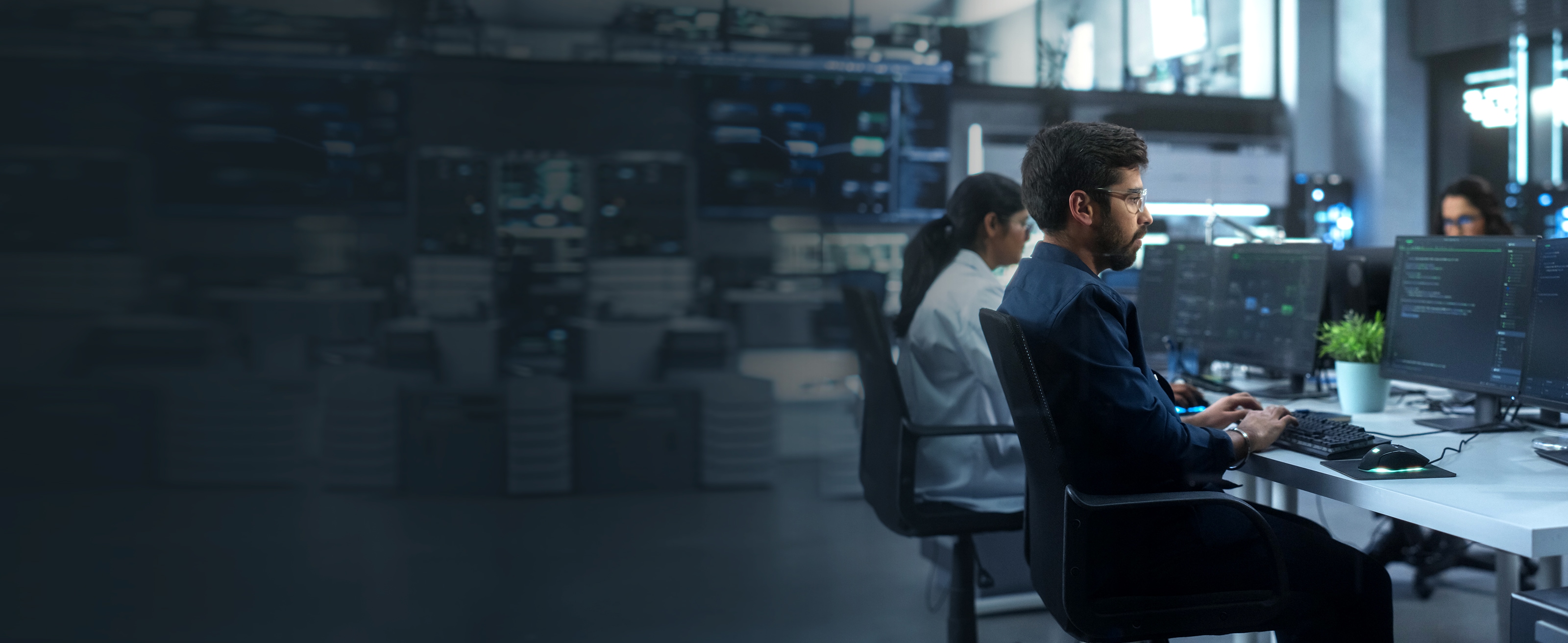 ワークスペースで椅子に座ってデスクトップコンピュータで作業をする従業員。