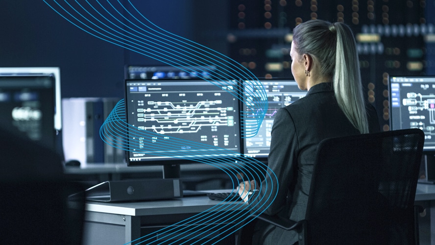Employee sitting at her desk and working on two large monitors