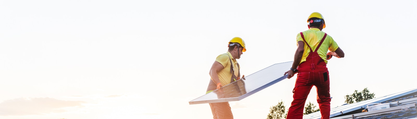 Two workers carry a solar panel